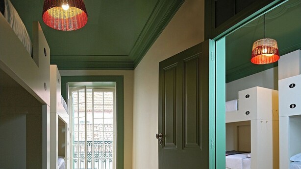 A compact room with bunk beds, a door, and a window with a view. - 29 Madeira Hostel (Funchal)