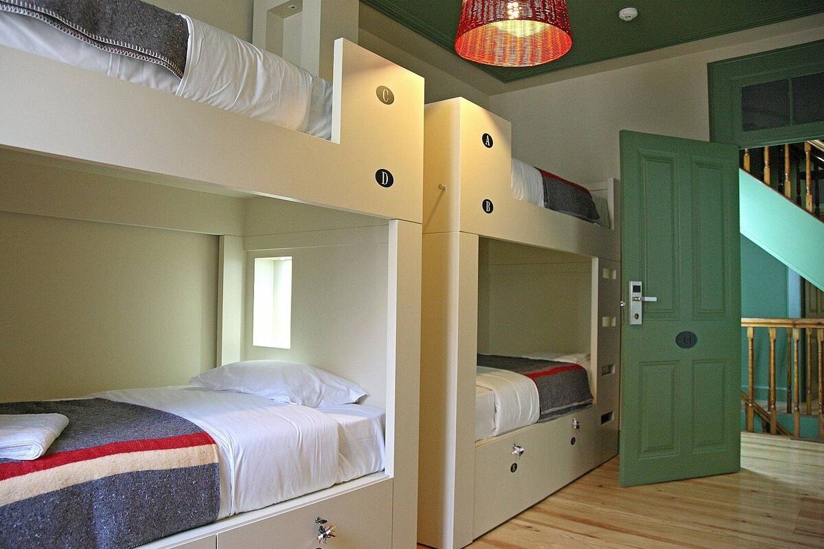 A room with bunk beds, a window, a door, and a staircase.