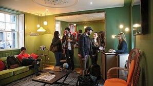 A hotel lobby with a green wall, a reception desk, a sofa, and a coffee table with a globe and books. - 29 Madeira Hostel (Funchal)