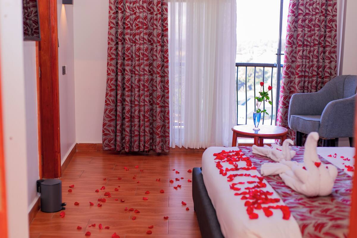 Ein Hotelzimmer mit Bett, Stuhl, kleinem Tisch und einem Balkon mit Blick.