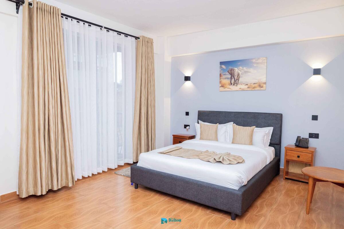 Ein modernes Hotelzimmer mit einem großen Bett, Holzboden und einem Gemälde einer Wüstenlandschaft an der Wand.