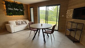 Un salon moderne avec une table de salle à manger ronde, un canapé blanc et une décoration murale sur le thème de la nature.