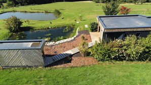 Un bâtiment moderne doté d’un toit plat, entouré d’une pelouse bien entretenue et d’un petit étang.