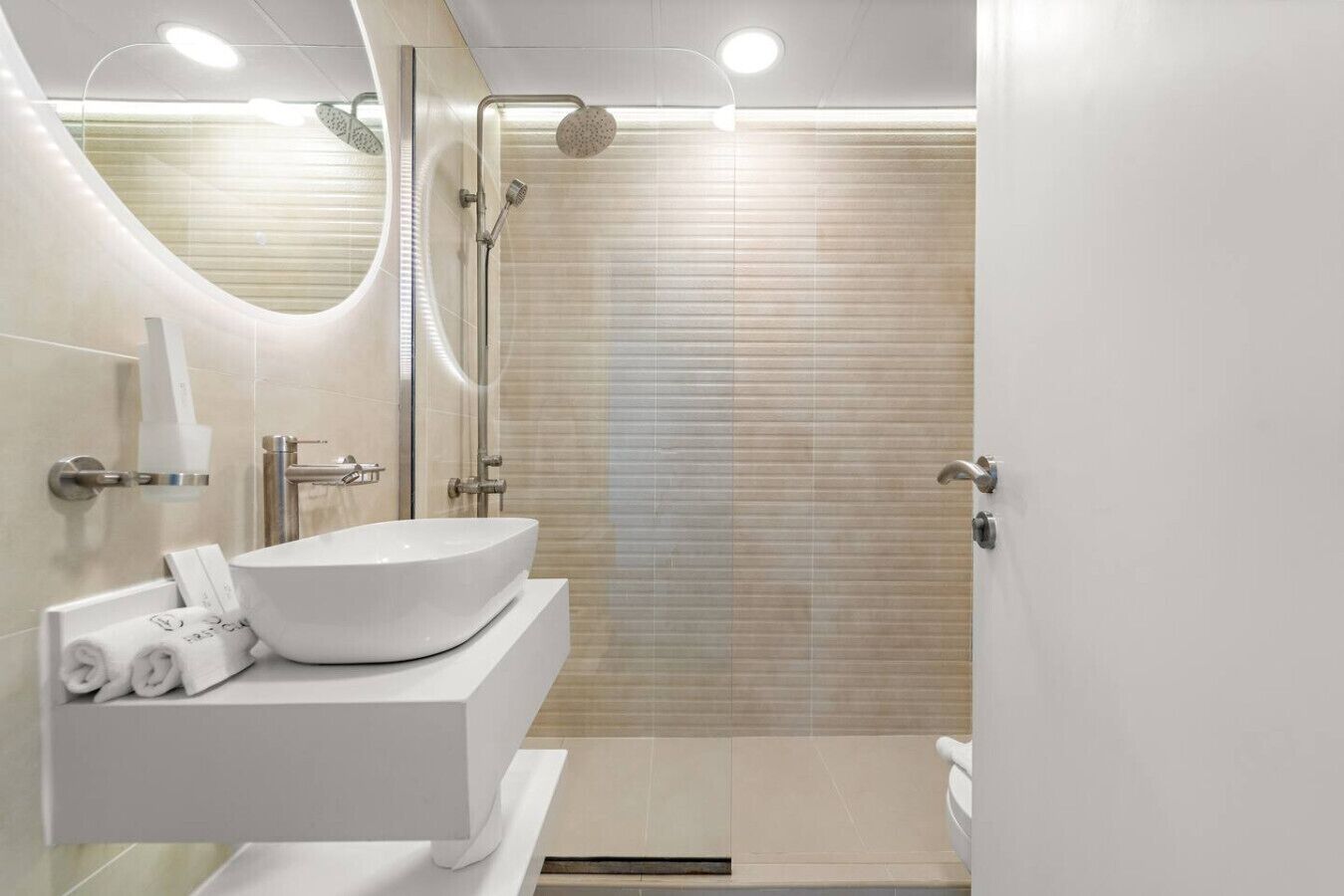 Un bagno moderno con un lavandino bianco grande, una doccia con porta in vetro e un WC.