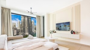 A modern hotel room with a large bed, a view of a cityscape, a small table with a vase, and a mounted TV. - Stylish 2BR Downtown Dubai with Skyline & Burj Khalifa Views (Downtown)
