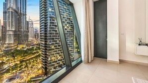 A modern apartment with a large panoramic window, a minimalist interior, and a view of a cityscape with high-rise buildings. - Stylish 2BR Downtown Dubai with Skyline & Burj Khalifa Views (Downtown)