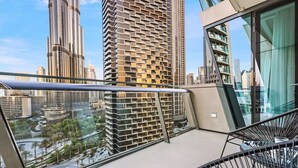 A balcony with a view of high-rise buildings, a glass railing, and a modern chair. - Stylish 2BR Downtown Dubai with Skyline & Burj Khalifa Views (Downtown)