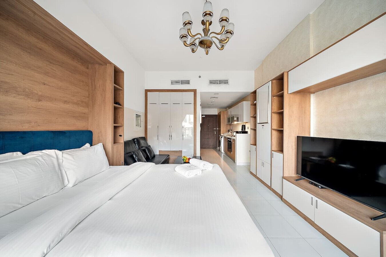 Ein modernes Hotelzimmer mit einem großen Bett, einem Fernseher und einer Küchenzeile.
