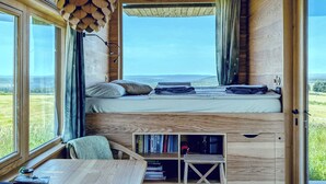 Une cabane confortable avec un lit, une petite table et une bibliothèque.