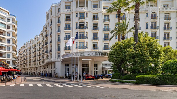 Un grand hôtel à étages, doté d’une entrée imposante et d’un mât pour drapeau.