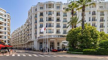Un grande hotel con diversi piani, un ingresso ben visibile e un'asta con bandiera.