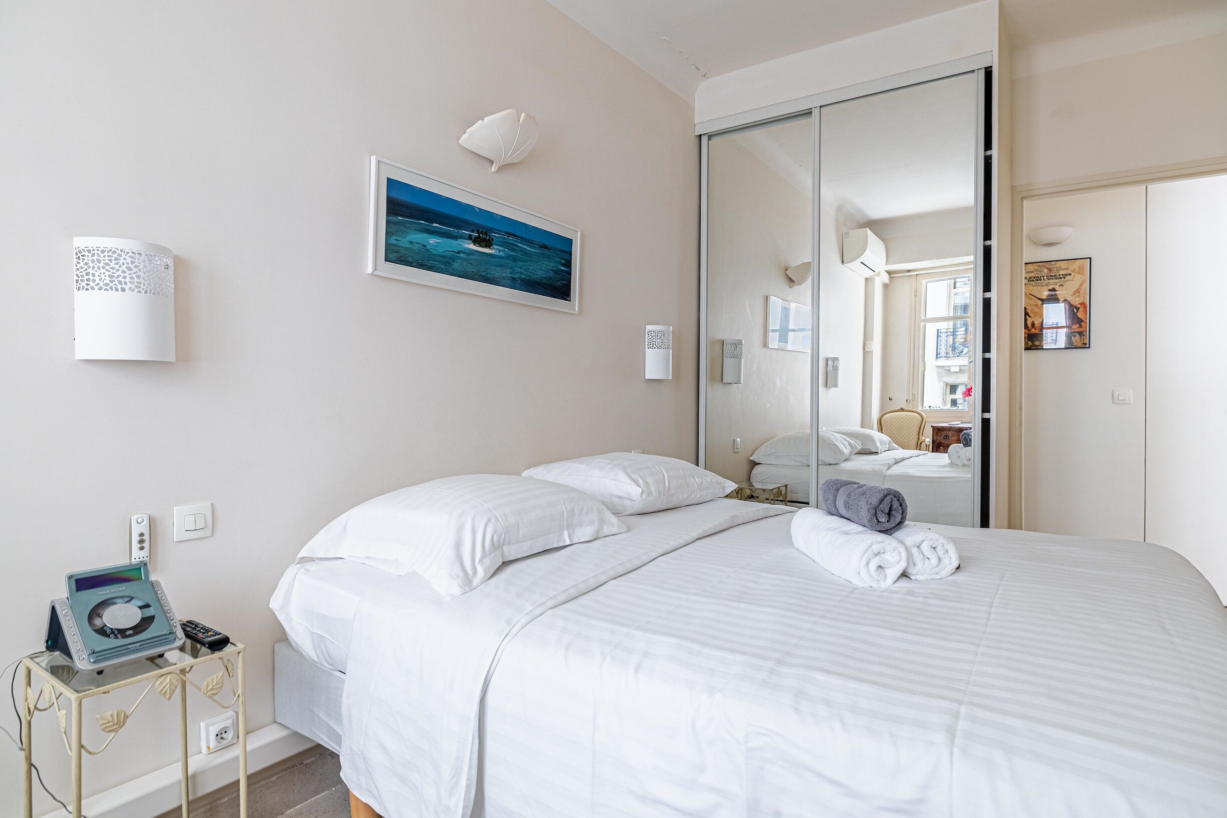 Una camera d'albergo con un letto, un comodino con una lampada, un quadro e una porta scorrevole per il bagno.