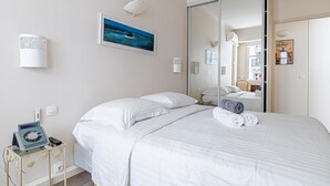 Une chambre d’hôtel avec un lit, une table de chevet avec une lampe, un tableau et une porte coulissante donnant sur la salle de bain.