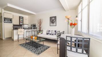 A modern living room with a sofa, coffee table, and a dining area with chairs.