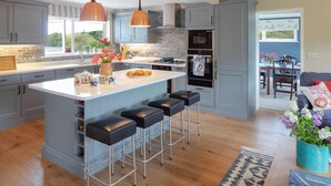 A modern kitchen with a large island, bar stools, pendant lighting, and a view to the dining area. - Luxury, spacious holiday home in St Mawes (St Mawes)