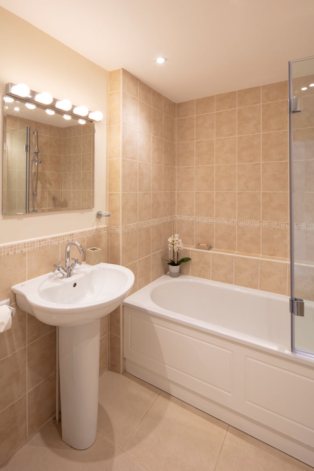 A bathroom with a sink, mirror, and bathtub.