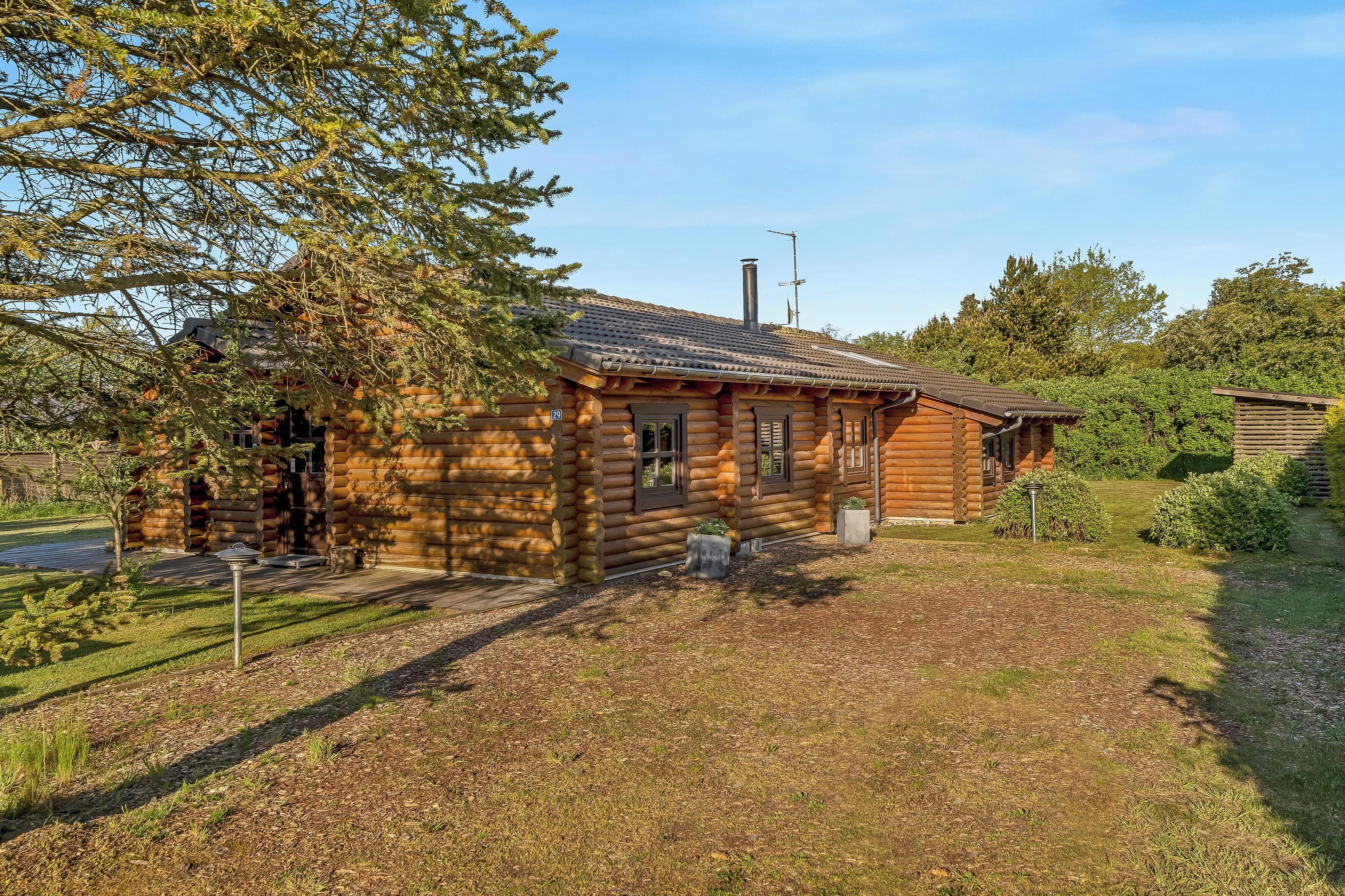 A log cabin with a tiled roof, a chimney, and a small porch.