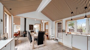 Une cuisine moderne avec un coin repas, de grandes fenêtres et une cuisinière intégrée.