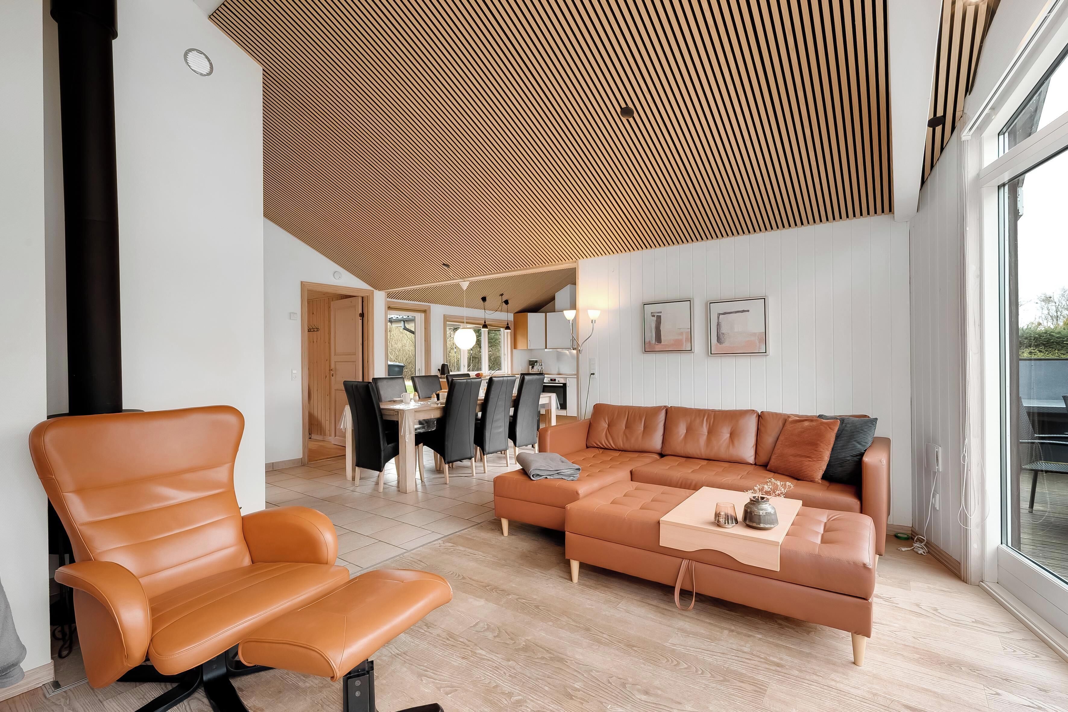 Un salon moderne avec un canapé en cuir marron, un fauteuil assorti et un coin repas comprenant une table et des chaises.