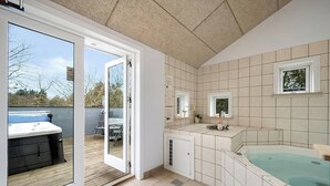 Une salle de bain avec une baignoire, une douche et des toilettes. Il y a une fenêtre donnant sur l’extérieur.