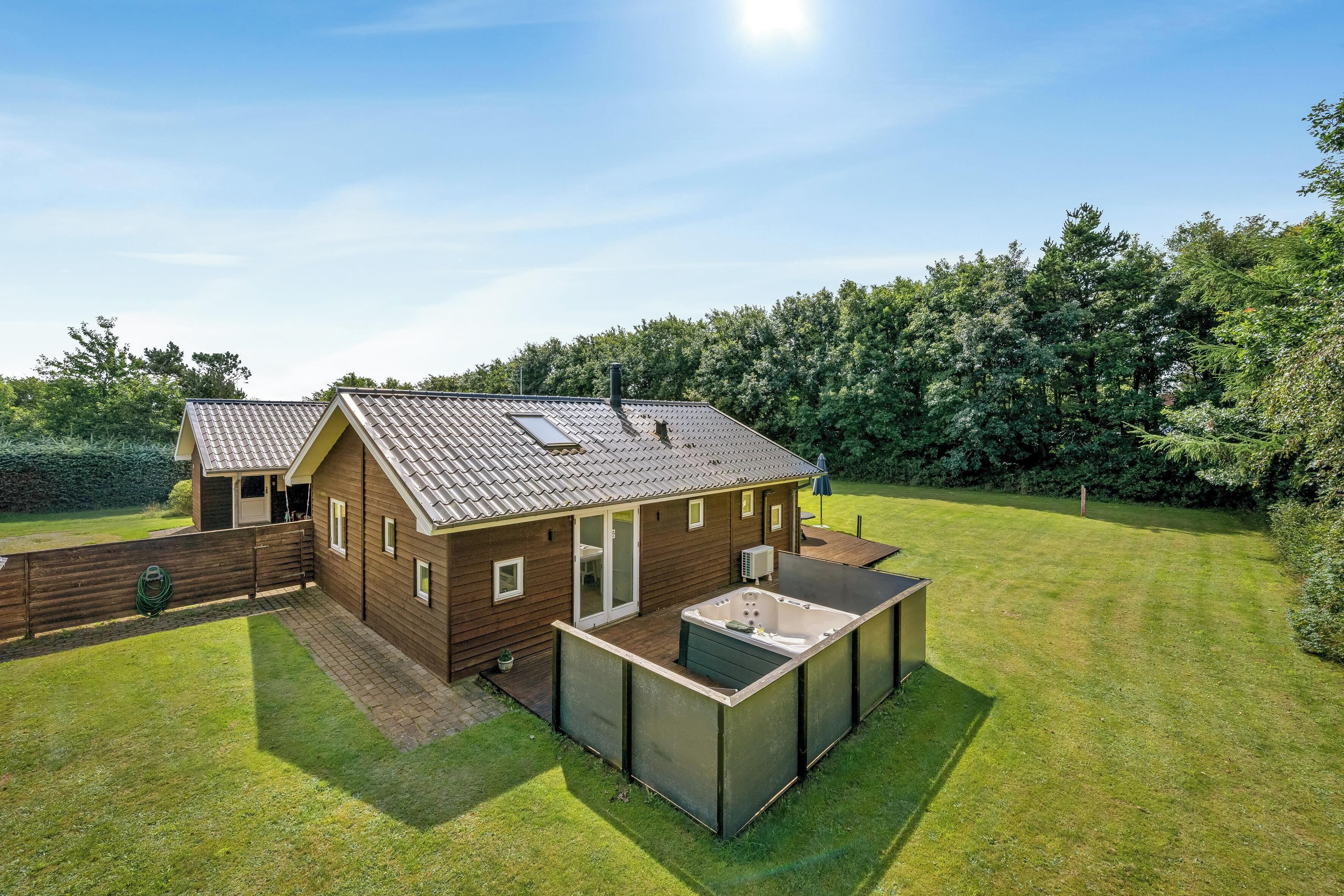 Een houten huis met twee verdiepingen, een terras en een jacuzzi.