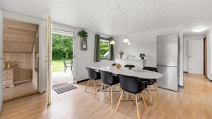Una cocina moderna con encimera blanca, sillas negras y un refrigerador de acero inoxidable.