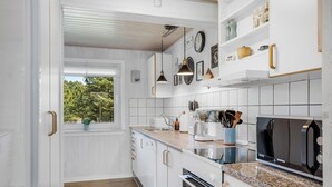 Una cocina moderna con armarios blancos, encimera de granito, horno empotrado y ventana con vistas a zonas verdes.