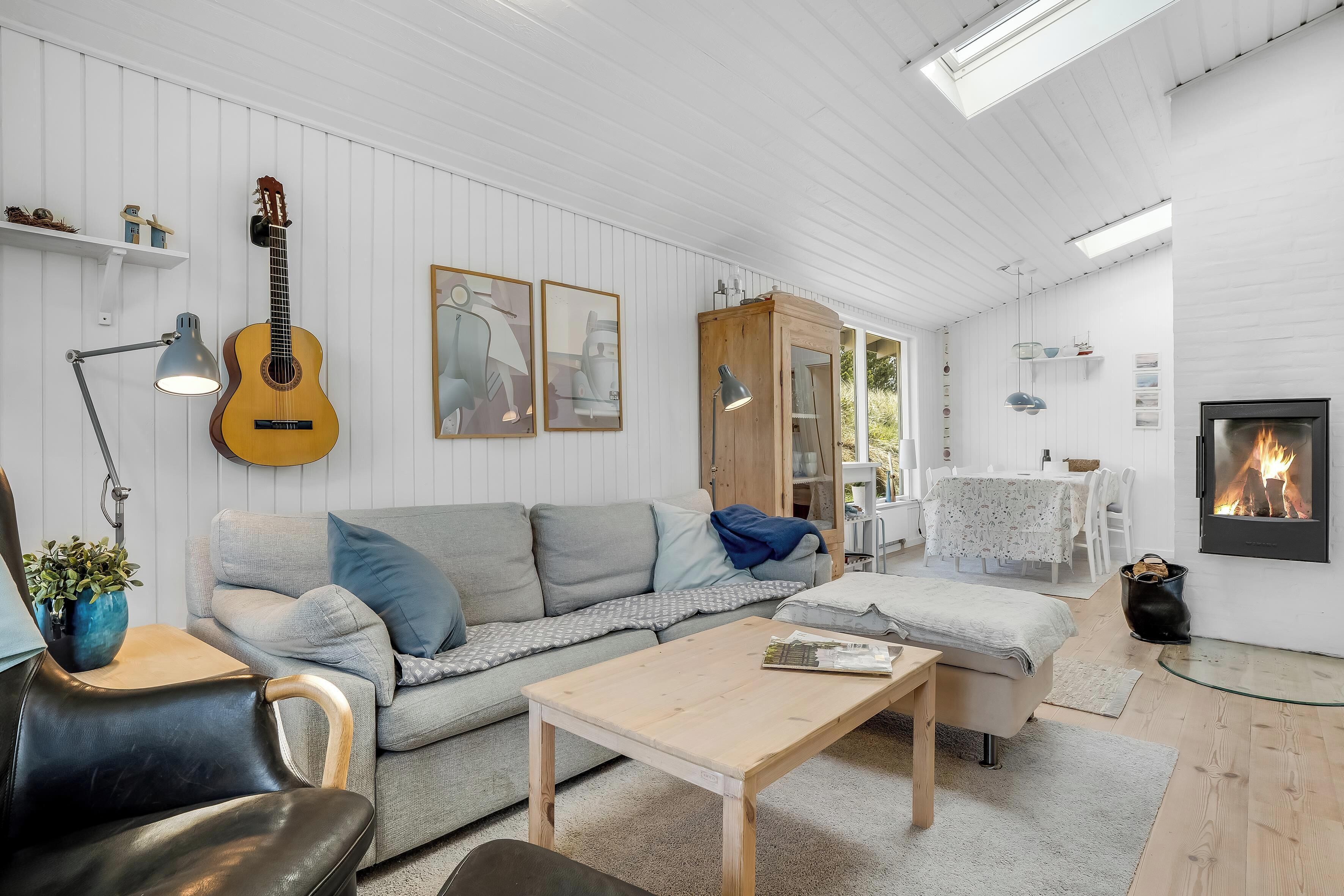 Una sala de estar acogedora con un sofá, una mesita de centro, una guitarra y una chimenea.