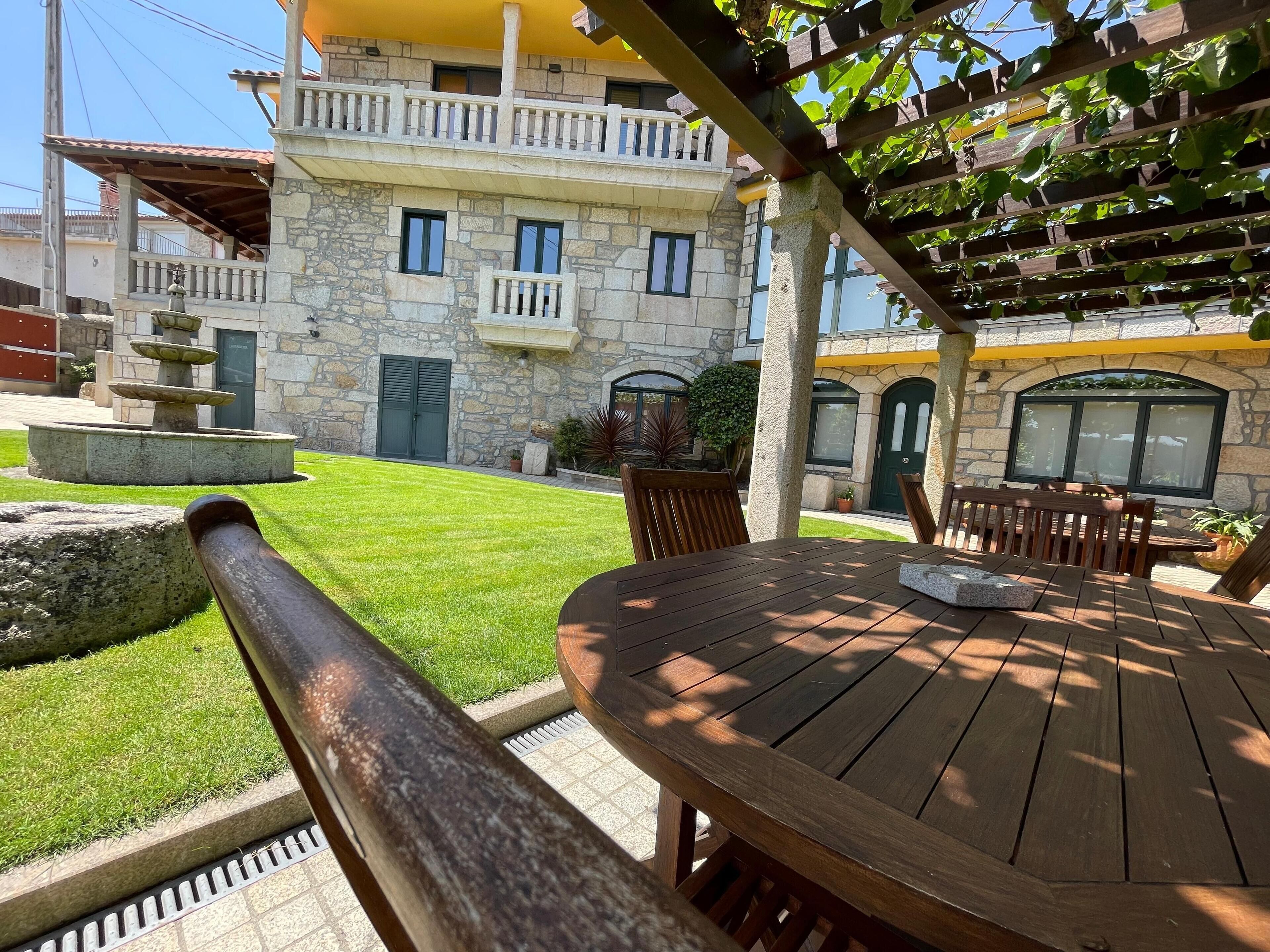 A stone building with a balcony, a fountain, and a well-maintained lawn.