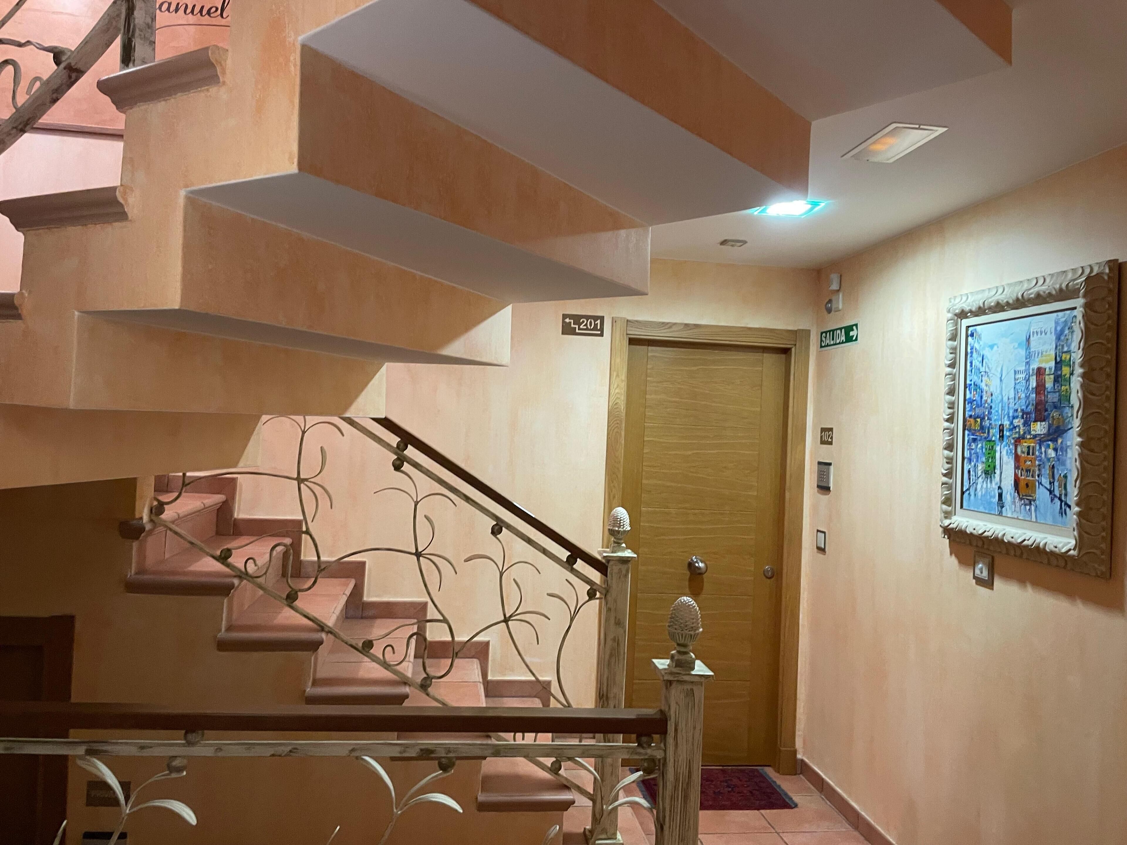 A staircase with a handrail, a wooden door, and a painting on the wall.