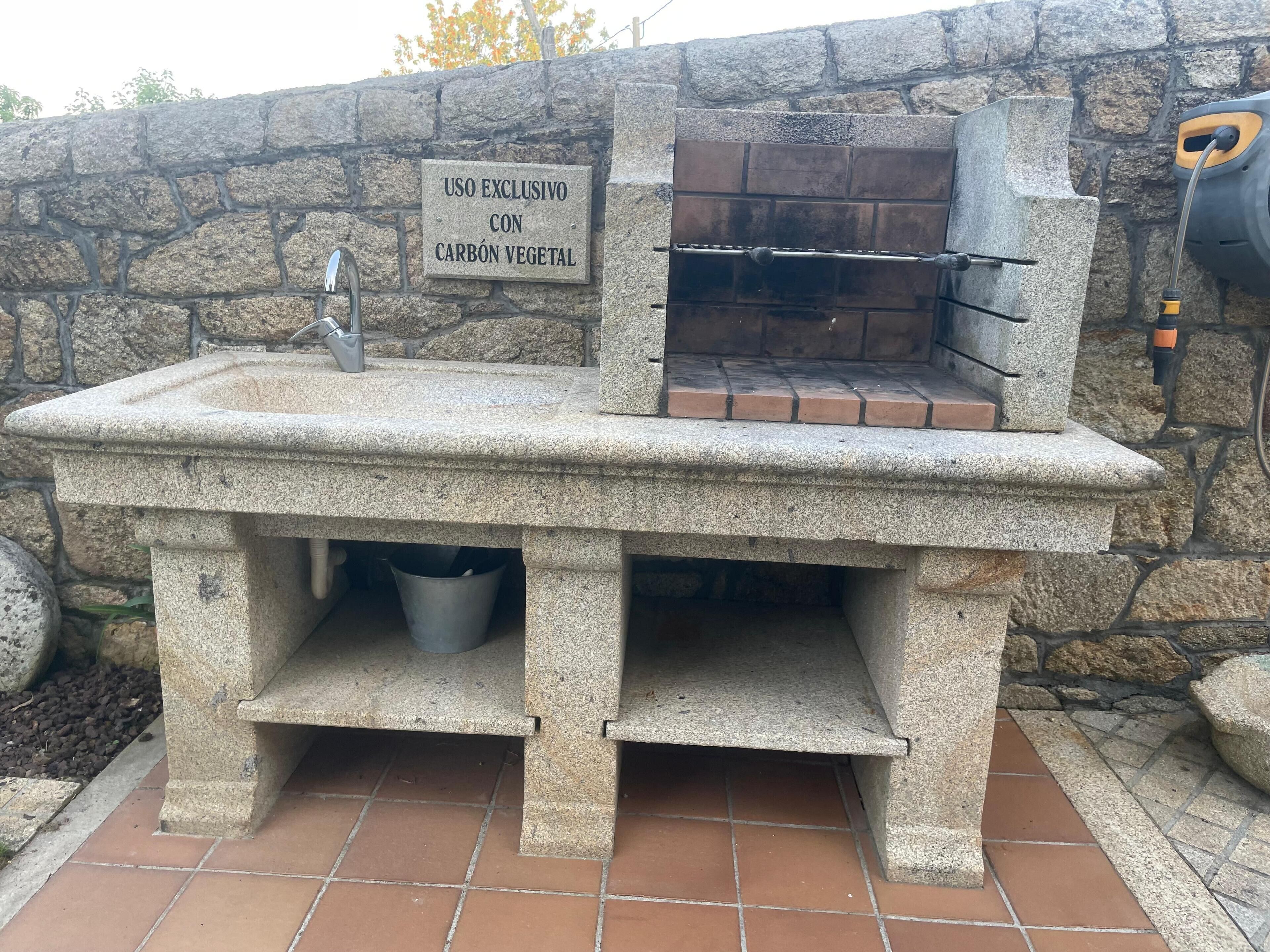 Een buitenkeuken van natuursteen met een bordje dat exclusief gebruik met houtskool aangeeft.