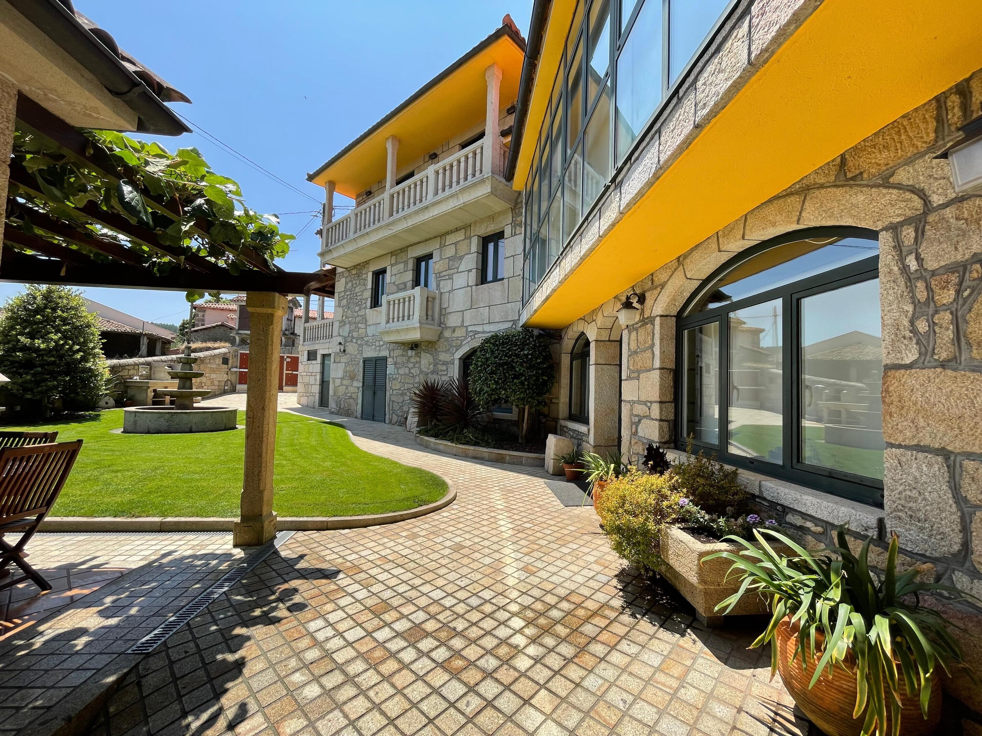 A courtyard with a fountain, a pergola, and a seating area.