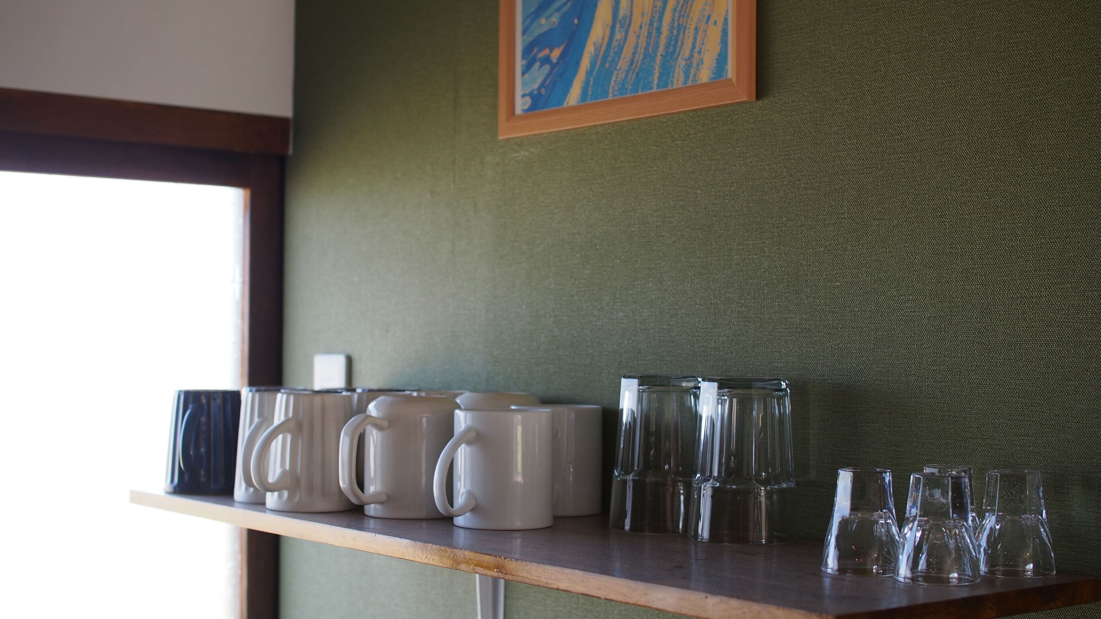 A shelf with various mugs and glasses.