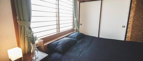 A bedroom with a bed, a bedside table with a lamp, a vase with a plant, and a sliding door.
