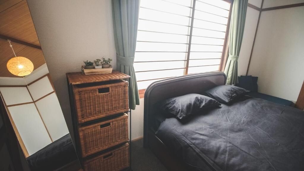 A bedroom with a bed, a bedside table with a lamp, and a window with curtains.