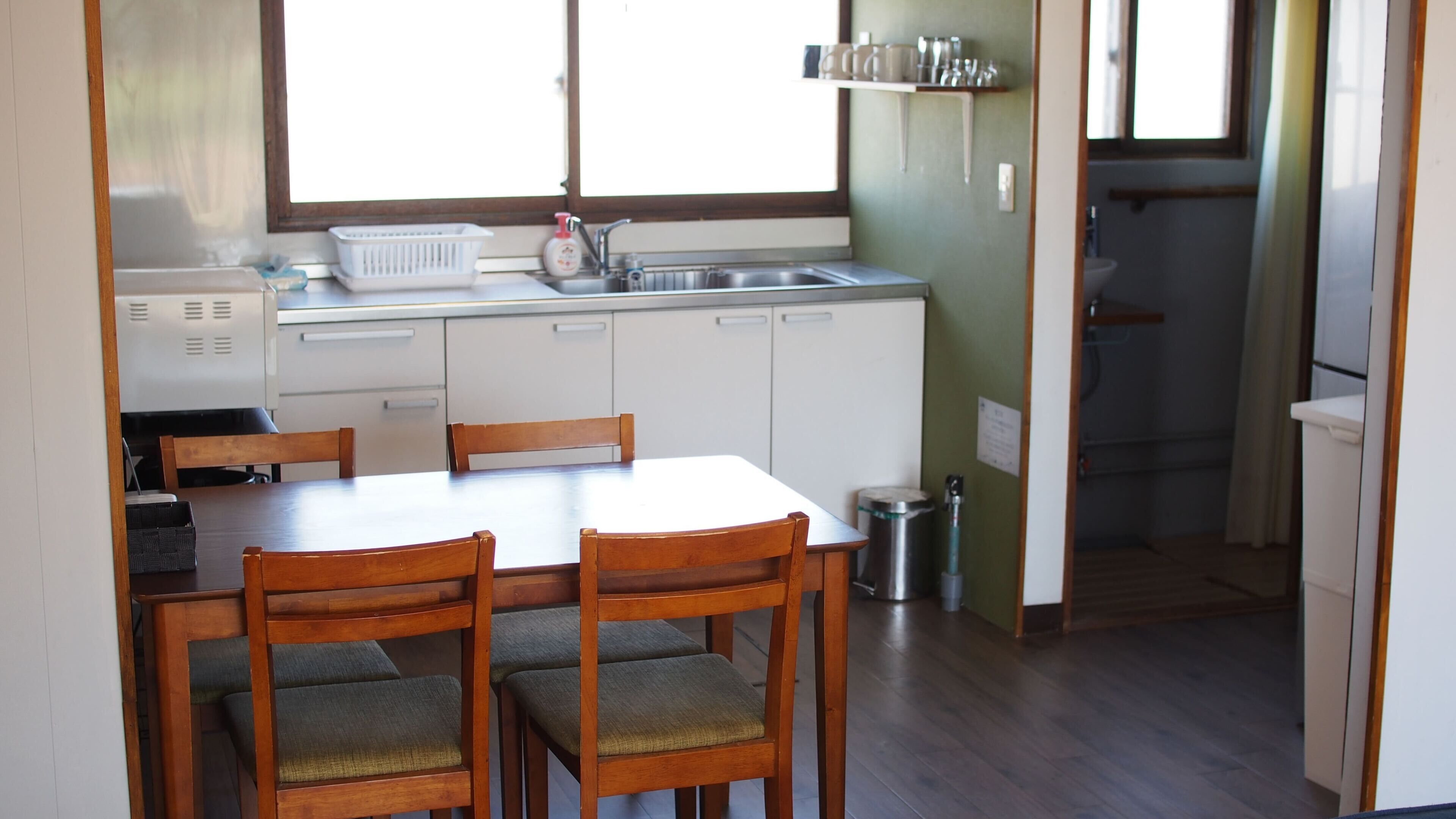 A compact kitchen with a dining table, chairs, a sink, and cabinets.