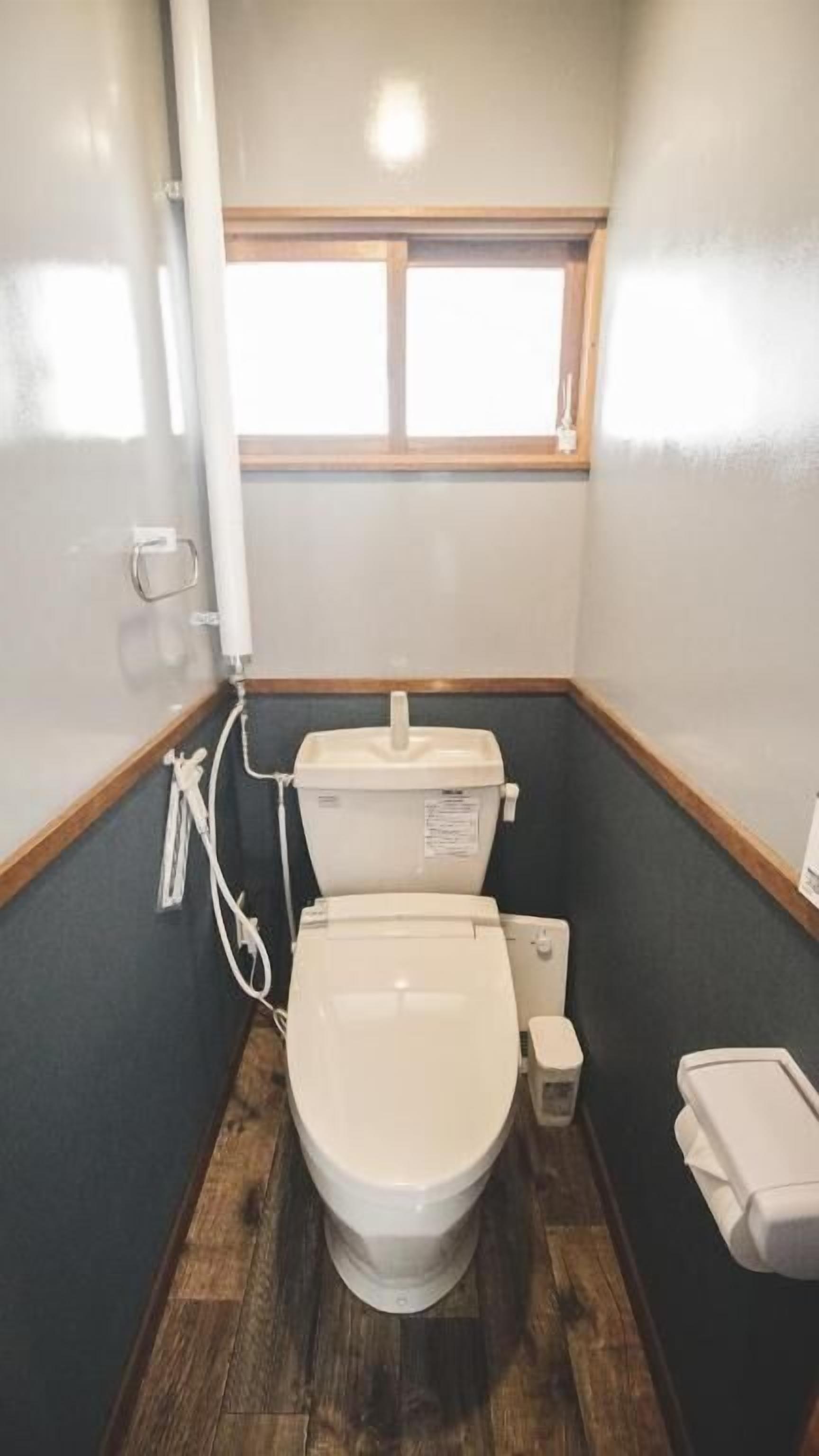 Een kleine, praktische badkamer met toilet, bidet en een raam boven het toilet.