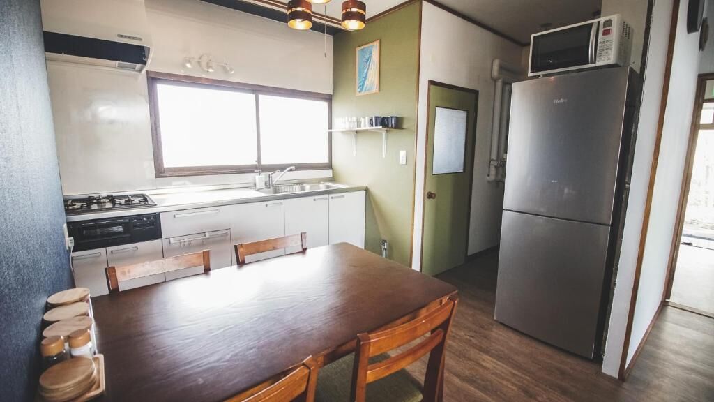 Uma cozinha compacta com mesa de jantar, geladeira e micro-ondas.