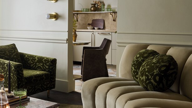A modern living room with a sofa, a coffee table, and a dining area with a chair and a small table. - Designed for two couples, friends or a family, flat four is one of the edgiest suites in Hotel Julie (Stratford)