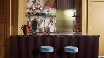 A kitchen with a marble backsplash, a built-in stove, and two bar stools.