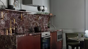 A modern kitchen with a marble countertop, stainless steel appliances, and a dining area with a round table and chairs.
