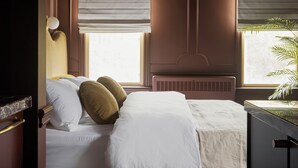 Ein Schlafzimmer mit Bett, Nachttisch, Lampe und einem Fenster mit Jalousien.