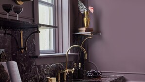 Un baño moderno con encimera de mármol, accesorios dorados y una ventana.