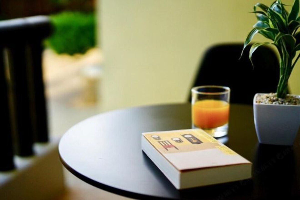 A table with a book, a glass of orange juice, and a potted plant.