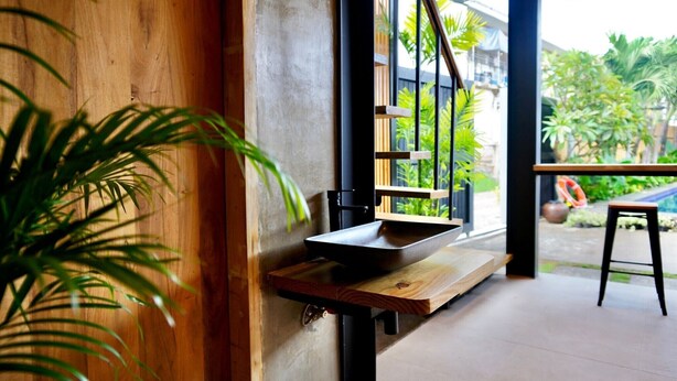 Une salle de bain moderne avec un meuble-lavabo en bois, un évier noir et une fenêtre donnant sur un jardin.