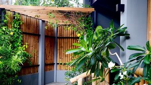 Un espace extérieur moderne agrémenté d’un chemin en pierre, de clôtures en bambou et d’une végétation luxuriante.