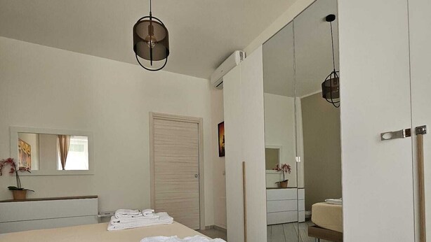 A modern bedroom with a bed, a mirror, and a wardrobe.