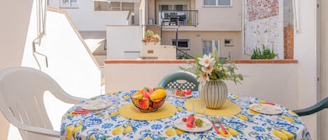 A balcony with a table set for dining, a chair, and a potted plant.