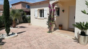 A house with a paved courtyard, a white door, and a window with shutters. - Large villa with swimming pool in a residential area close to the beach. (Frontignan)