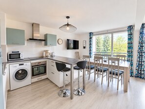 Una cucina moderna con lavatrice, microonde e zona pranzo con sedie e tavolo.